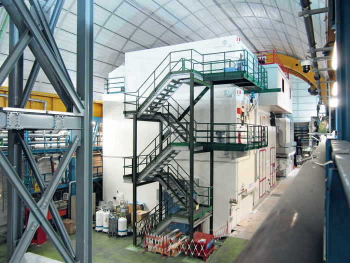 Das Experiment CRESST Ein weißer Kasten in einer großen Halle an dessen Wand eine Trepe nach oben führt.