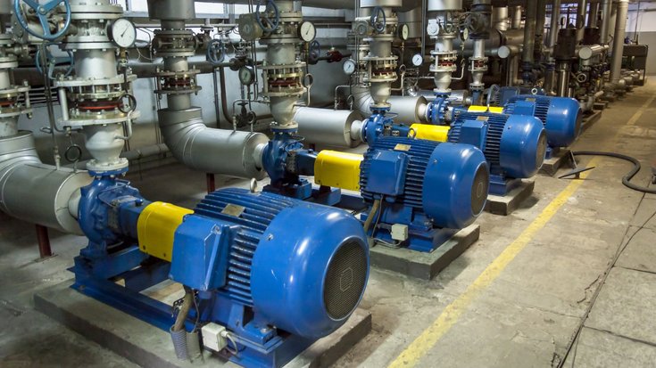 Vier blaue Zylinder mit Rohren verbunden in einem Maschinenraum