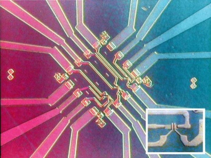 Aus vier senkrecht aufeinander stehenden Richtungen führen jeweils vier Leiterbahnen zentral auf eine elektronische Chipstruktur hin.