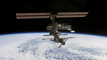 Raumstation fliegt im All, im Hintergrund ist die Erde als wolkenbedeckte Oberfläche zu sehen.