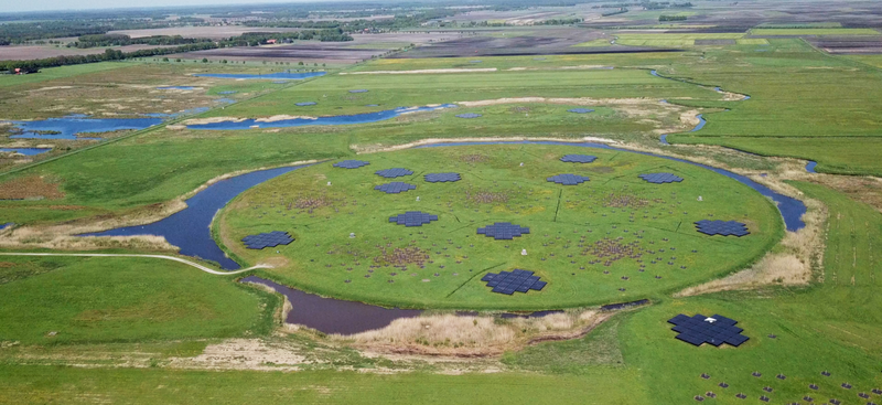 Luftbild einer Wiese auf die mehrere technische Modulplatten aufgebracht sind