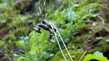 Schwebendes, schwarzes Flugobjekt, das mit zwei Drähten verbunden ist