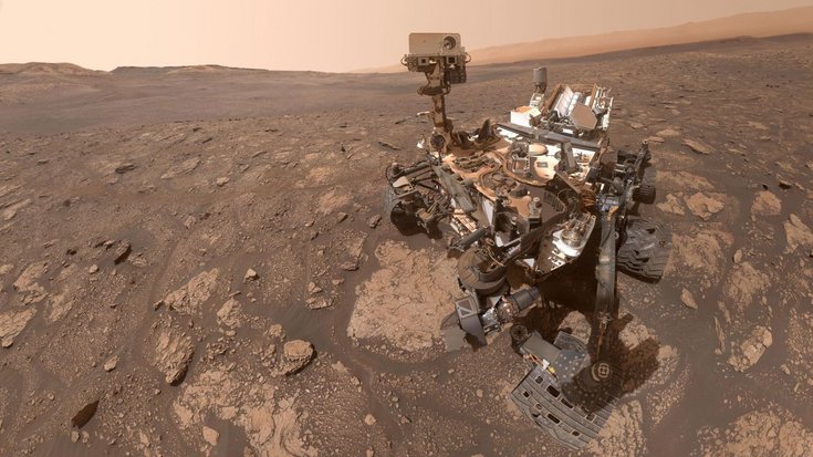 Ein fahrbarer Roboter steht auf der felsigen Marsoberfläche