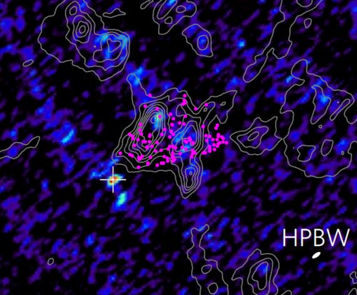 Ausschnitt der Molekülwolke, die Strahlungsintensität ist falrbig kodiert, Kontourlinien zeigen die Geschwindigkiet des gases im Inneren der Wolke. Ein Kreuz markiert eine kompakte Strahlungsquelle im Inneren der Wolke.