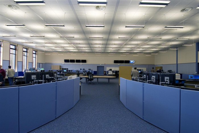 Das Kontrollzentrum am CERN Ein großer Raum, mit Computerplätzen, die in mehren großen Kreisen angeordnet sind.