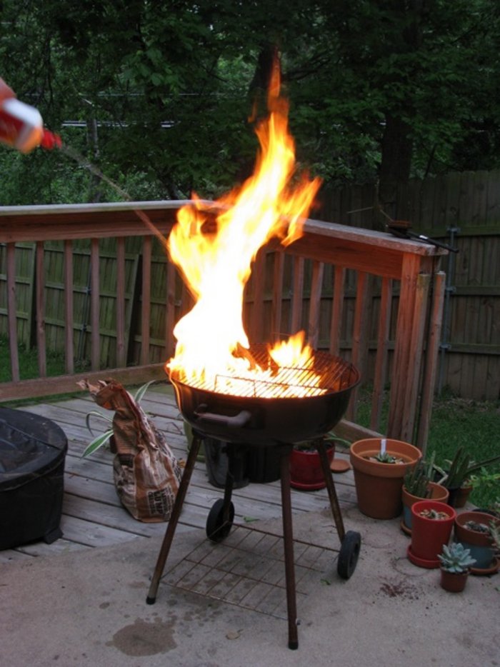 Entflammter Holzkohlegrill Flammen schlagen aus einem Holzkohlegrill.