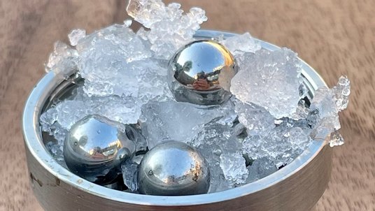 Eis in einem metallenen Behälter durchmischt mit metallenen Kugeln