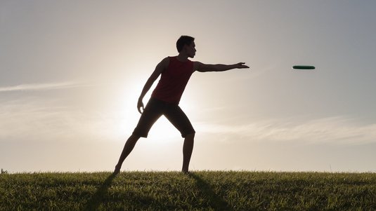 Person wirft eine Frisbeescheibe