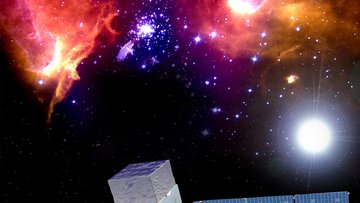 Vor dem Hintergrund des Weltalls schwebt eine metallische Konstruktion, von dessen quaderförmigem Rumpf sich zwei mit Solarzellen bedeckte Tragflächen ausbreiten.