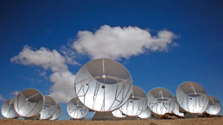 Mehrere Antennenschüsseln vor einem leicht bewölkten Himmel.