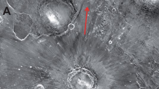 m Mittelpunkt des Bildes ein Krater, von dem radial helle Streifen ausgehen.