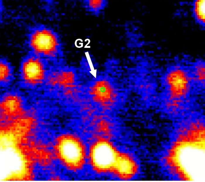 G2 passiert Schwarzes Loch Ein kleiner Kreis im Zentrum markiert die Position des Schwarzen Lochs. Direkt daneben ist das mit einem Pfeil markierte Objekt G2. In der Umgebung sind weitere helle Punkte.