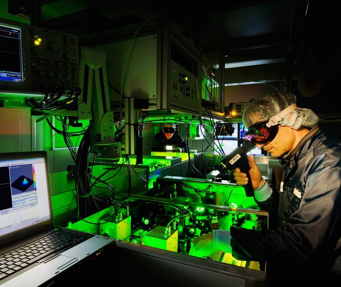 Hochleistungslaser DRACO Zwei Wissenschaftler mit Schutzbrillen an der Laseranlage, in der grünes Licht leuchtet.
