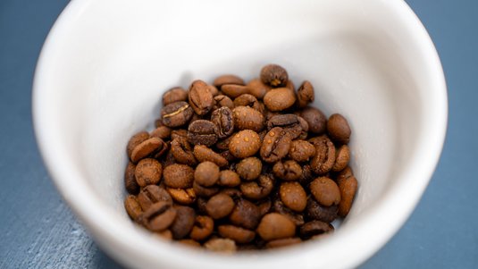Kaffeebohnen in einer Tasse mit Wassertropfen benetzt