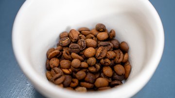 Kaffeebohnen in einer Tasse mit Wassertropfen benetzt