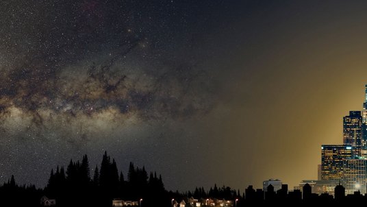 Verlauf eines Nachthimmels: Links ist ein dunkler Nachthimmel über einem Wald zu sehen, in der Mittel ein etwas hellerer Himmel über leicht besiedelter Gegend, rechts eine Großstadt mit hell erleuchtetem Nachthimmel