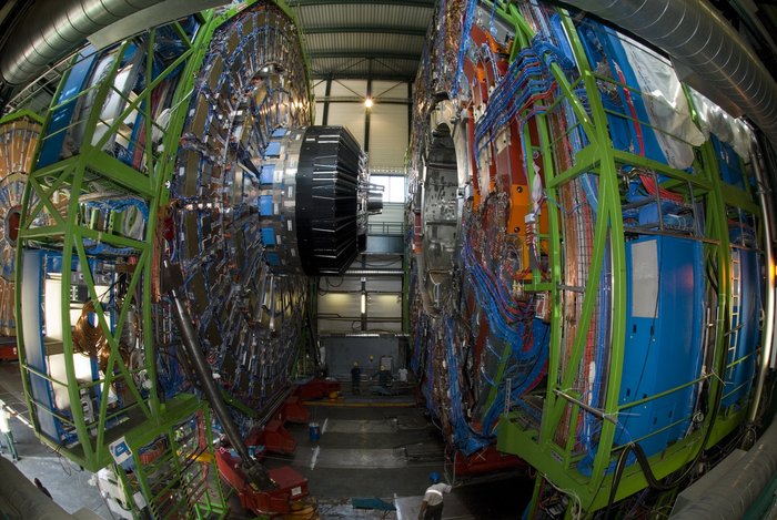 Der CMS-Detektor ie beiden Hälften des CMS-Detektors, die einige Meter auseinander geschoben sind. Es sind Stahl, Elektronik und metallische Komponenten zu erkennen.