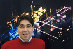 Porträtfoto des Wissenschaftlers mit Detailaufnahme eines optischen Tisches im Hintergrund