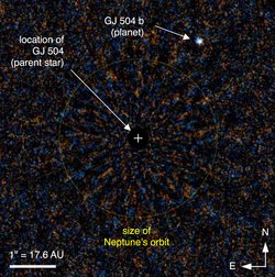 Rechts oben kleiner Lichtpunkt in einer ansonsten verrauschten Fläche, ein Kreuz markiert die Position des Sterns. Zum Vergleich ist die Größe der Neptun-Umlaufbahn eingezeichnet, Gliese 504b liegt deutlich außerhalb.