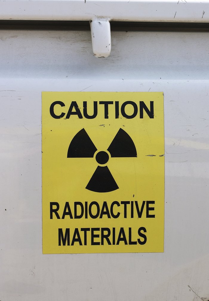 Warnung vor radioaktivem Material Gelbes Warnschild mit Symbol für Radioaktivität auf einer Metallwand.