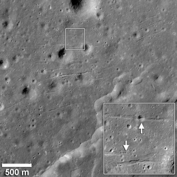 Graue Fläche, mit Kratern übersäät. Zwischen den Kratern verlaufen lange horizontale Strukturen