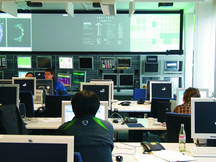Steuerzentrale des Jülicher Tokamaks TEXTOR Wissenschaftler sitzt aufmerksam in einem Raum, darin eine Menge Steuer- und Computerbildschirme.