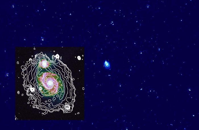 Radiokarte der Spiralgalaxie M 51 Dunkler Hintergrund. In der Mitte ist eine kleine helle Spiralgalaxie zu sehen. Darum herum viele kleinere helle Flecken.
