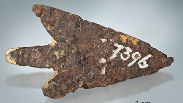 Ein Stück rostiges Eisen in Pfeilform, darauf ist in weiß die Zahl 7396 geschrieben. 
