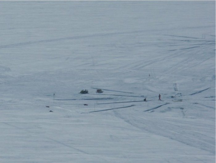 Messstation in der Antarktis Foto. Auf einer weißen Eisfläche sind Stangen und Rohre zu erkennen.