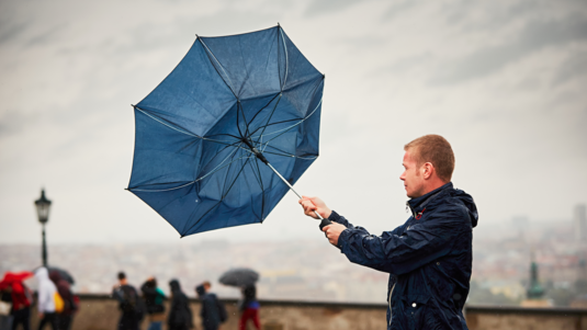 Mann hält einen umgeklappten Regenschirm