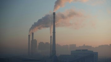 Rauchende Schornsteiner einer großen Fabrik vor einem trüben Himmel