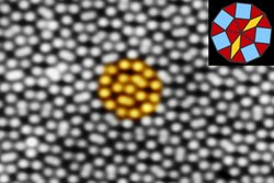Die einzelnen Oberflächenatome der Quasikristallschicht erscheinen als symmetrisches Muster aus hellen Flecken vor dunklem Hintergrund. Sie sind quadratisch und dreieckig angeordnet mit einem Abstand von weniger als einem Nanometer zueinander.