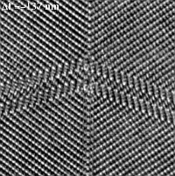 Kristallatome streng als weiße Punkte auf schwarzer Fläche angeordnet, Struktur pfeilförmig zugespitzt