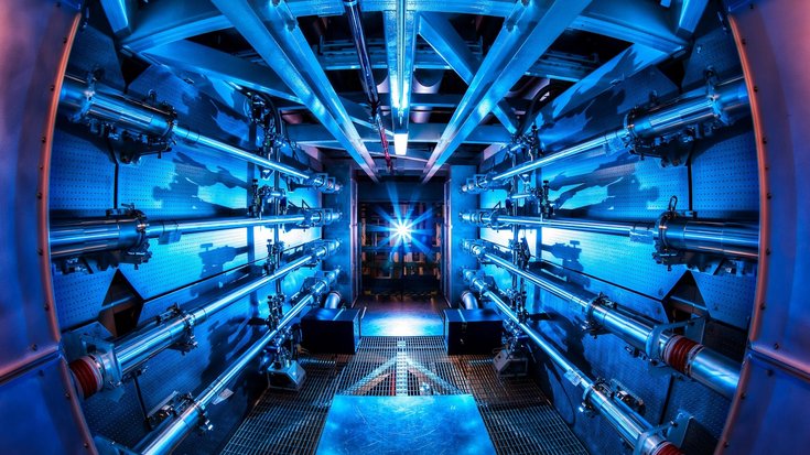 National Ignition Facility | Bildquelle: Damien Jemison Blau beleuchtete Kammer mit Röhren, die auf eine Lichtquelle zulaufen