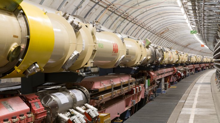 Entland eines Tunnels steht eine längliche technische Anlage, die aus runden Rohrenstücken zusammengesetzt ist.