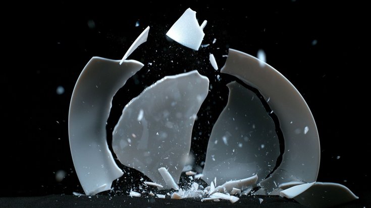 Das Bild zeigt den Moment, in dem ein Teller mit der Kante auf den Boden fällt und in größere und kleinere Bruchstücke zersplittert.