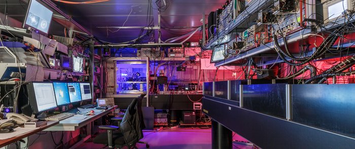 Prototyp eines Quantencomputers Geräte mit vielen Kabeln in einem Arbeitsraum mit Computern, Tischen und Stühlen.