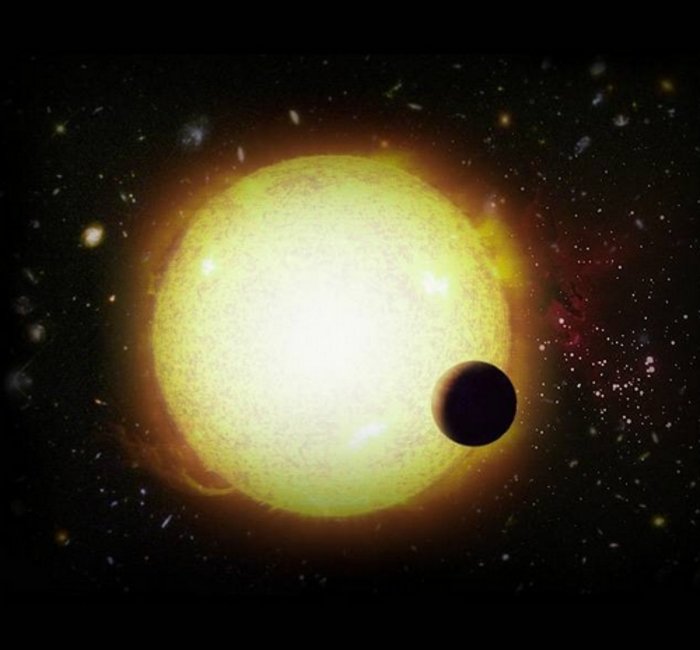 Transit eines Exoplaneten vor seinem Stern Vor dem hell leuchtenden Ball eines Sterns steht die dunkle Scheibe eines kleineren Objekts. Im Hintergrund sind weiter entfernte Sterne zu erkennen.