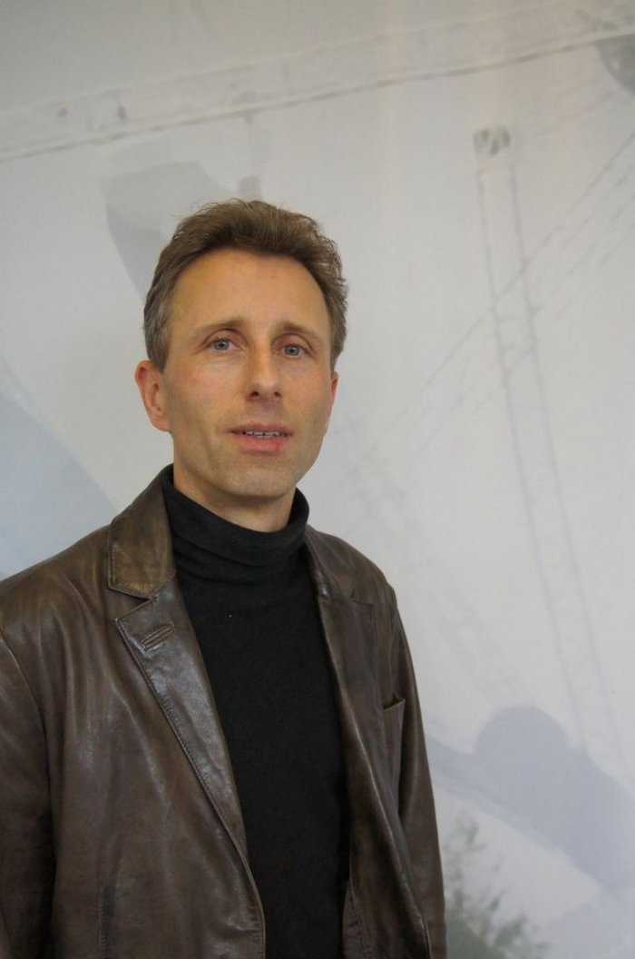 Helmut Wiesemeyer Helmut Wiesemeyer ist ein Mann Mitte vierzig mit kurzen dunklen Haaren. Er trägt einen schwarzen Rollkragenpullover und darüber eine braune Lederjacke.