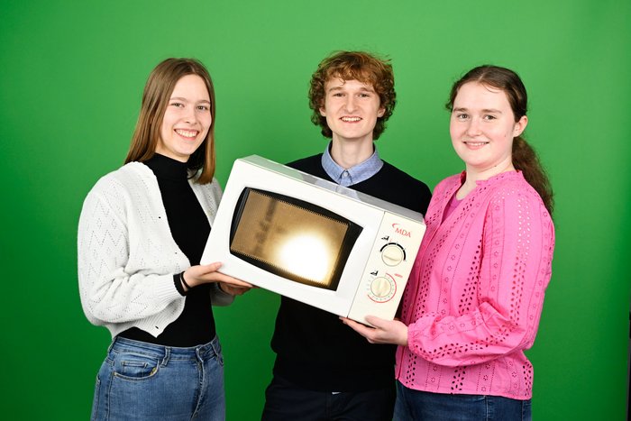 Henrik Laurin Herrmann, Céline Laurel Herrmann und Clara Marie Scherenberger Drei Jugendliche halten eine Haushaltsmikrowelle