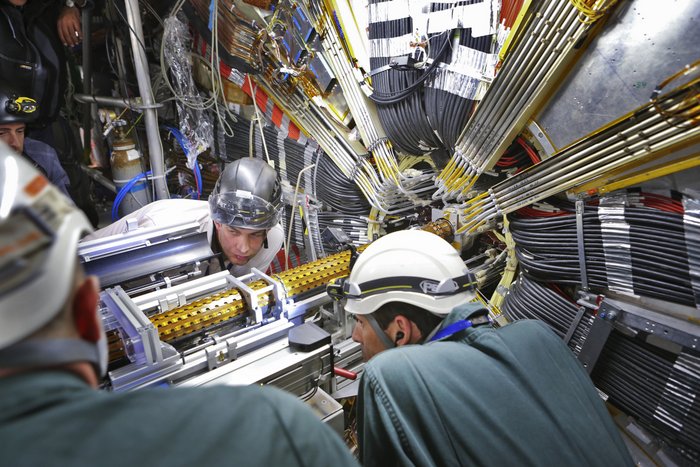 Insertable B-Layer im ATLAS-Experiment Männer schauen kritisch auf die rohrförmige Lage, im Hintergrund komplexe Verkabelungen.