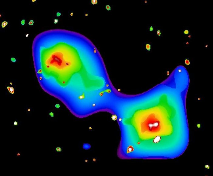 Galaxienhaufen im Röntgenlicht Falschfarbenaufnahme: Diffuse Wolke; innen weiß, nach außen schalenartig erst Rot, dann Gelb, Grün und Hellblau; schließlich ins Blau des übrigen Bildes übergehend