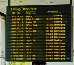 Große elektronische Tafel am Flughafen mit Infromatonen zu den Flügen, gelb leuchtende Buchstaben auf schwarzem Display