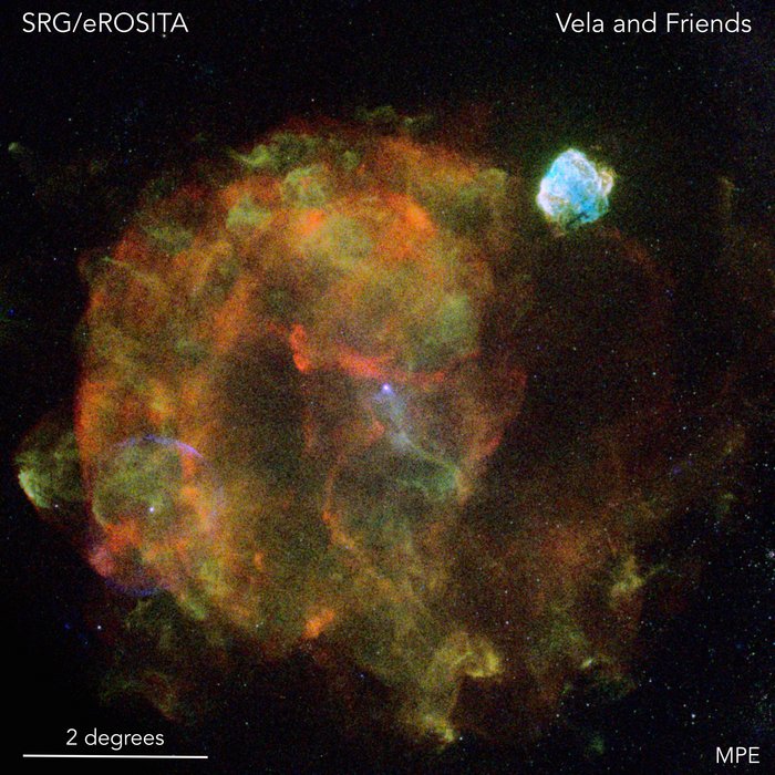 Runde, wabernde, grün-orange Masse im Weltall; rechts oben davon eine kleinere hellblaue