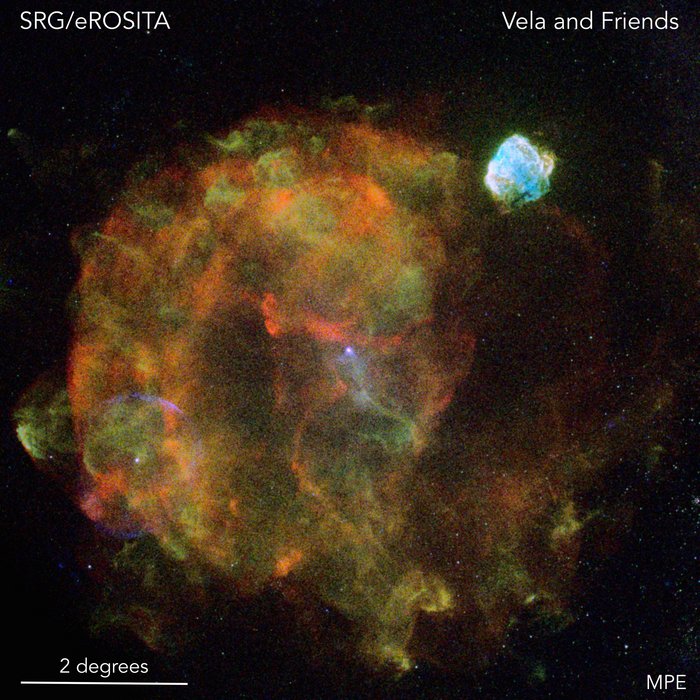 Überrest der Vela-Supernova Runde, wabernde, grün-orange Masse im Weltall; rechts oben davon eine kleinere hellblaue