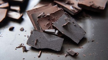 Das Bild zeigt kleine Stück von dunkler Schokolade, die aufeinanderliegen.