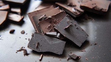 Das Bild zeigt kleine Stücke aus dunkler Schokolade, die aufeinanderliegen.