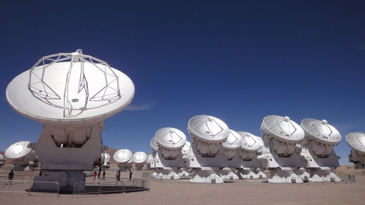 Mehrere weiße Radioantennen in der Wüste vor blauem Himmel