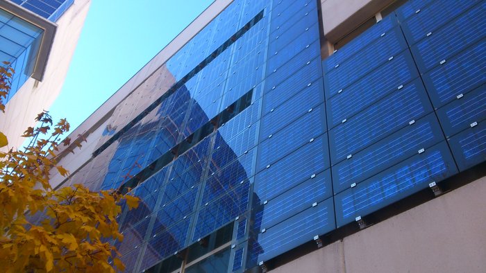 EIne Gebäudefassade in deren äußere Glaswand Solarmodule eingearbeitet sind.