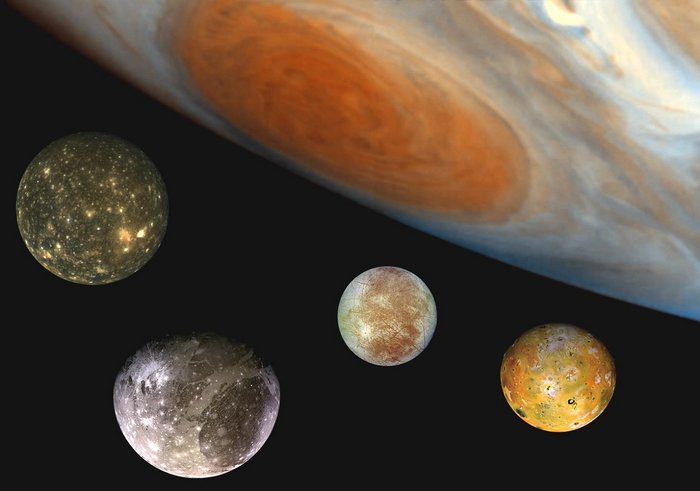 Die Galileischen Monde Das Bild zeigt im oberen Bereich einen Teil des Planeten Jupiter. Darunter sind vier Monde zu sehen, die alle eine unterschiedliche Oberflächenstruktur haben.